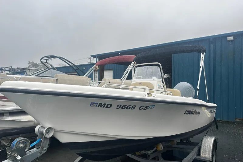 The Image of 2018 Key West 186 Center Console boat on trailer, parked near blue building. - 0