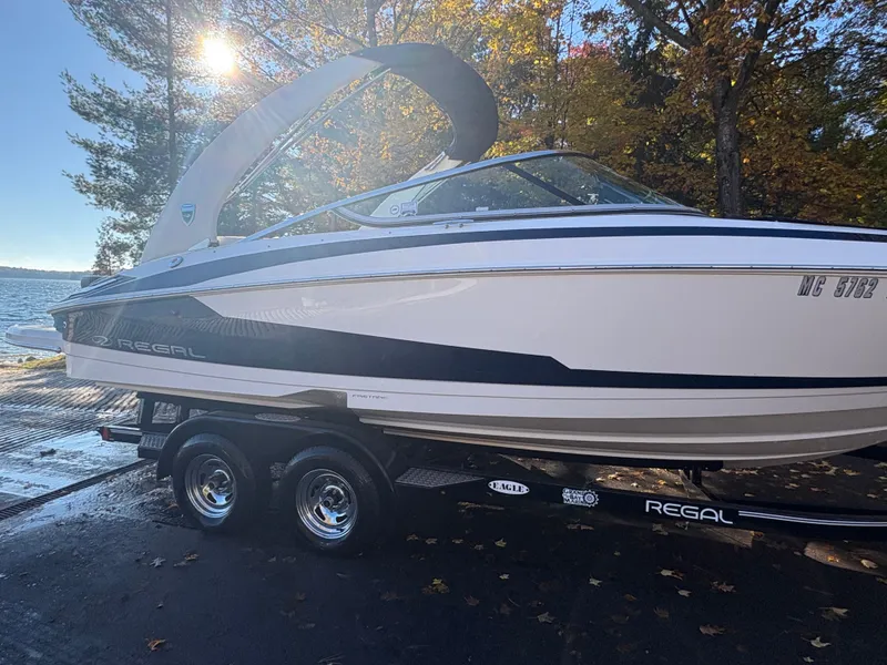 Slide: The Image of 2016 Regal 2300 Bowrider boat on trailer by lakeside, surrounded by autumn trees. - 14