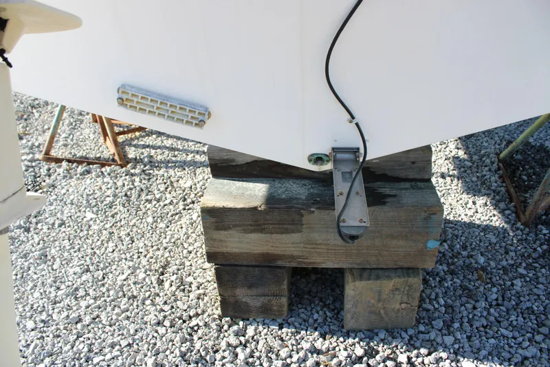 Slide: The Image of Pro-Line 29 Express O/B 2008 boat hull on wooden blocks, gravel background. - 11