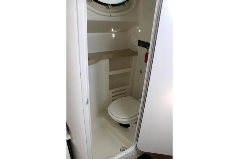 Slide: The Image of Compact bathroom in 2008 Pro-Line 29 Express O/B boat, featuring a toilet and storage shelf. - 26