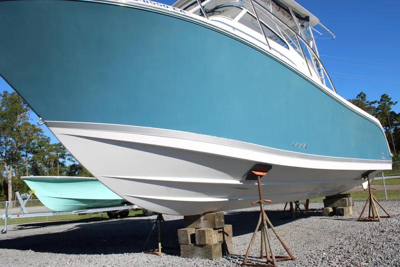 Slide: The Image of 2008 Pro-Line 29 Express O/B boat on stands, blue hull, outdoor display. - 37