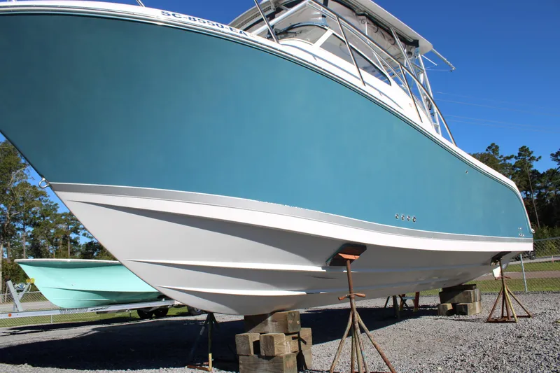Slide: The Image of 2008 Pro-Line 29 Express O/B boat on stands, blue hull, clear sky background. - 38