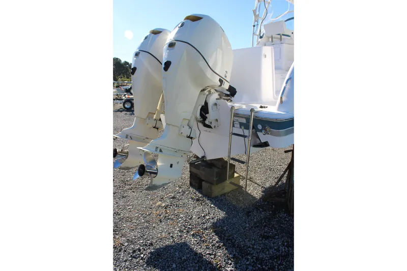 Slide: The Image of Twin outboard motors on a 2008 Pro-Line 29 Express O/B boat, parked on gravel. - 9