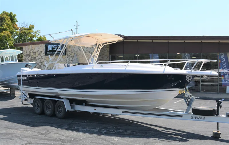 The Image of 2001 Intrepid 322 Cuddy boat on trailer, parked outdoors. - 0