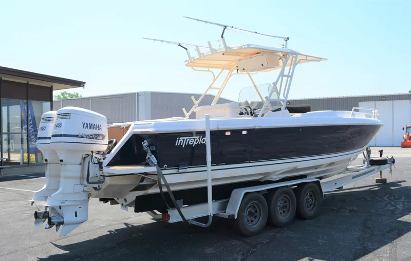 Slide: The Image of 2001 Intrepid 322 Cuddy boat on trailer with Yamaha engines, parked outdoors. - 2