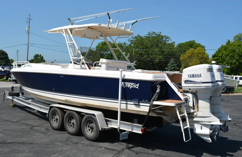 Slide: The Image of 2001 Intrepid 322 Cuddy boat on trailer with Yamaha outboard motor, parked outdoors. - 6