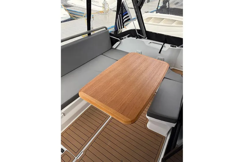 Slide: The Image of Interior of 2023 Beneteau Antares 9 with wooden table and gray seating. - 14