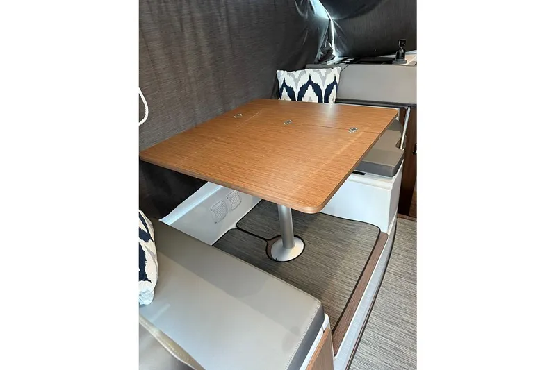 Slide: The Image of 2023 Beneteau Antares 9 interior dining area with wooden table and cushioned seating. - 23