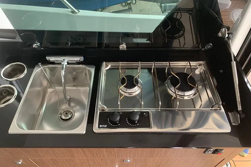 Slide: The Image of Compact kitchen area in 2023 Beneteau Antares 9 with sink and dual-burner stove. - 27