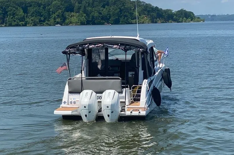 Slide: The Image of 2023 Beneteau Antares 9 boat cruising on a serene lake with lush green shoreline. - 4