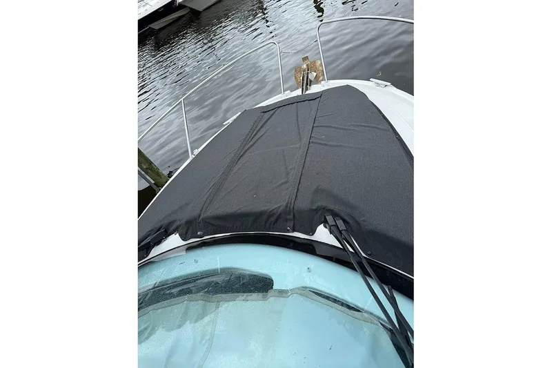 Slide: The Image of 2023 Beneteau Antares 9 boat with black cover on deck, docked by water. - 8