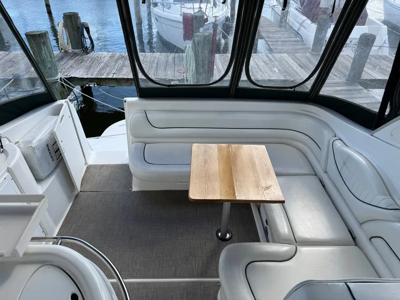 Slide: The Image of 2001 Maxum 3500 SCR boat interior with seating and wooden table, docked at marina. - 13