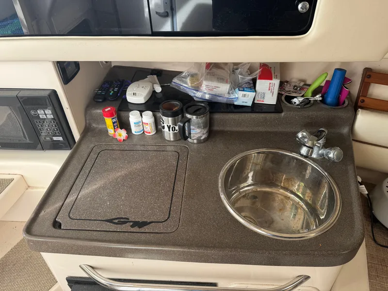 Slide: The Image of 2004 Grady-White Marlin 300 boat kitchenette with sink, countertop, and various items. - 19