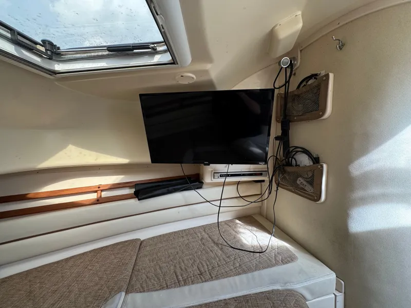Slide: The Image of 2004 Grady-White Marlin 300 cabin interior with TV and storage compartments. - 23