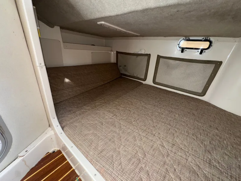 Slide: The Image of 2004 Grady-White Marlin 300 cabin interior with cushioned sleeping area and storage compartments. - 26