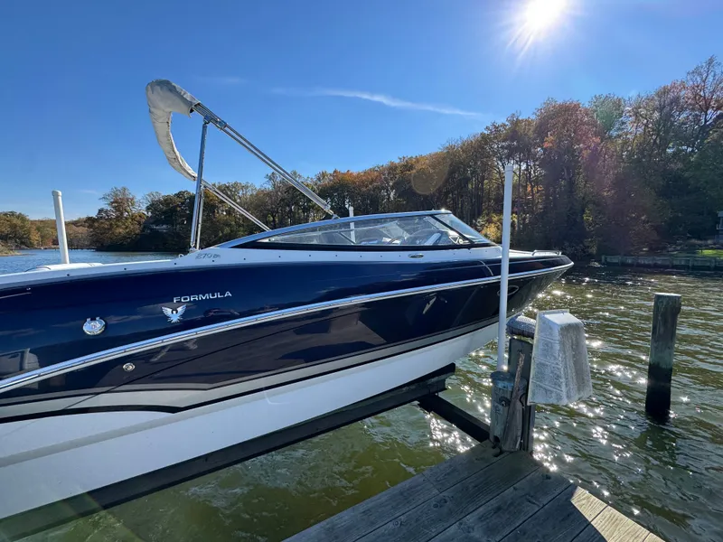 Slide: The Image of 2014 Formula 270 Bowrider docked on a sunny day by a wooded shoreline. - 2