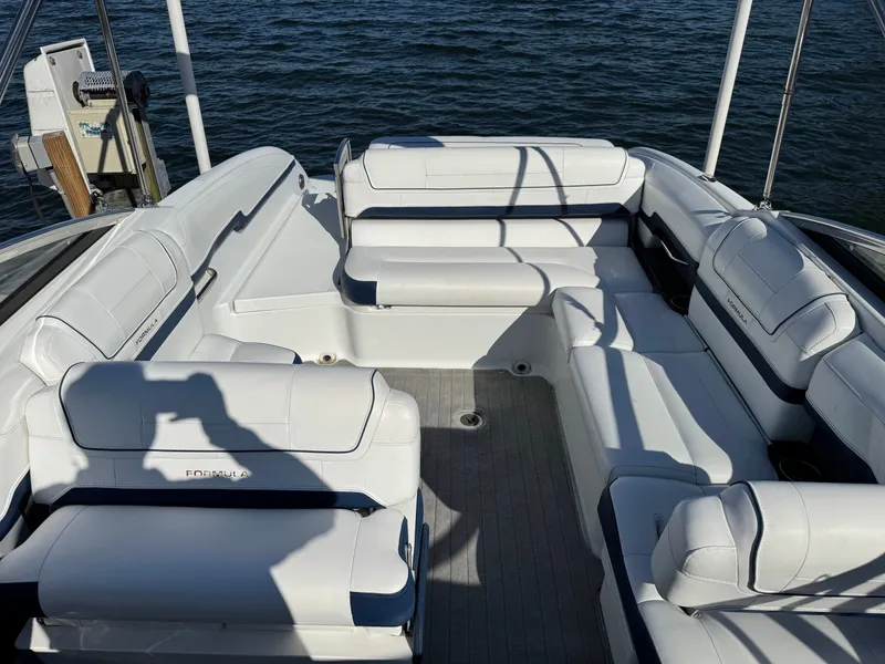 Slide: The Image of 2014 Formula 270 Bowrider boat interior with white seating, docked by the water. - 26
