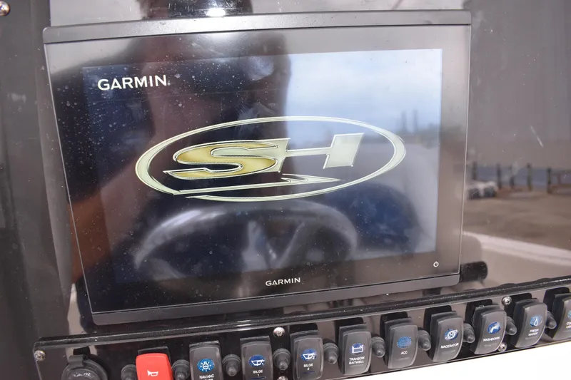 Slide: The Image of Garmin display on 2023 Sea Hunt Ultra 255 SE boat dashboard with control switches. - 24