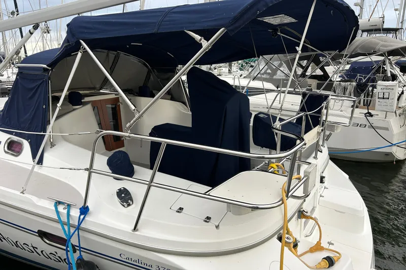 Slide: The Image of 2009 Catalina 375 sailboat docked, featuring blue canvas covers and stainless steel railings. - 2