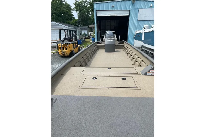 Slide: The Image of 2025 SeaArk 2672 CUB boat in a yard, near a blue building and forklift. - 4