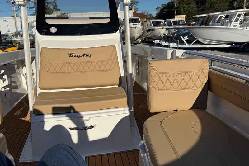 Slide: The Image of 2026 Bayliner Trophy T22CC boat interior with tan seating and wood flooring. - 11