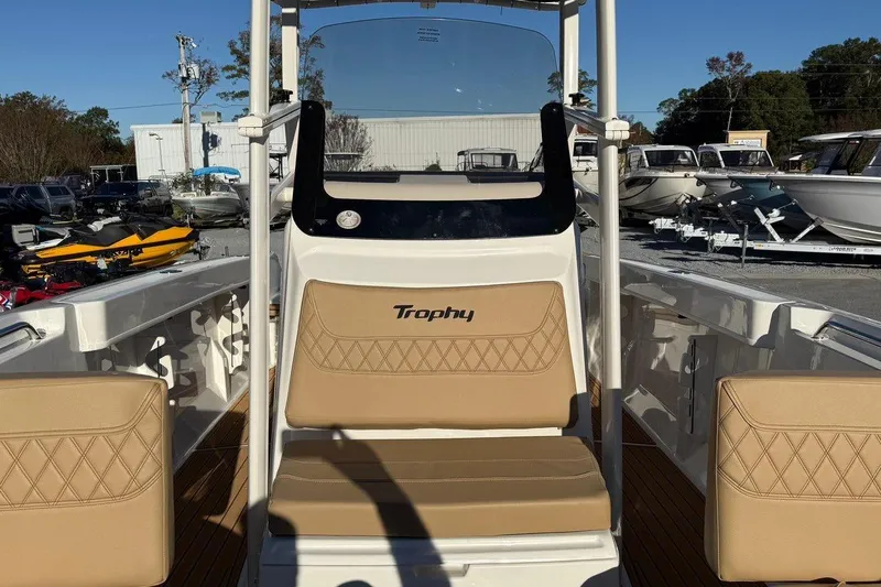 Slide: The Image of 2026 Bayliner Trophy T22CC boat interior with tan seating and console, displayed outdoors. - 15