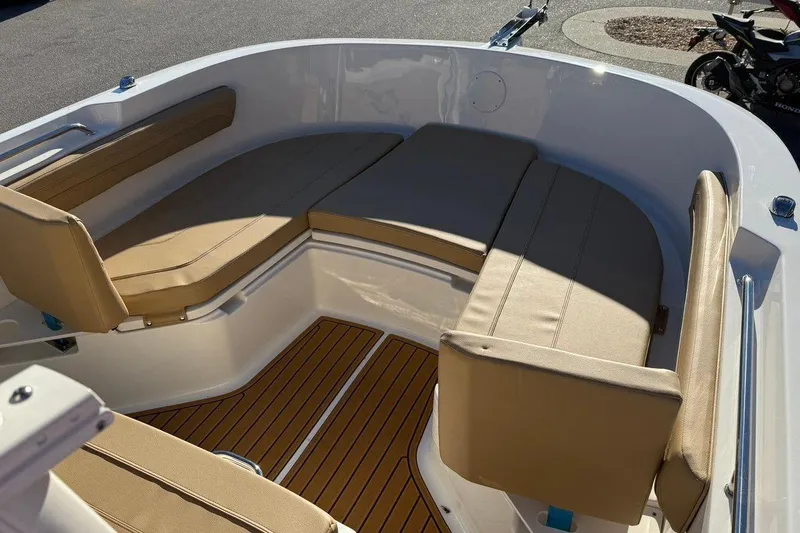 Slide: The Image of 2026 Bayliner Trophy T22CC boat interior with tan cushioned seating and wood-style flooring. - 17