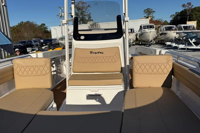 Slide: The Image of 2026 Bayliner Trophy T22CC boat interior with tan seating and console, in a marina setting. - 8