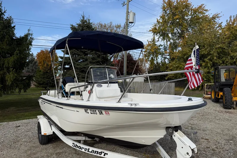 Slide: The Image of 2004 Boston Whaler 160 Dauntless boat on trailer with American flag, parked outdoors. - 1