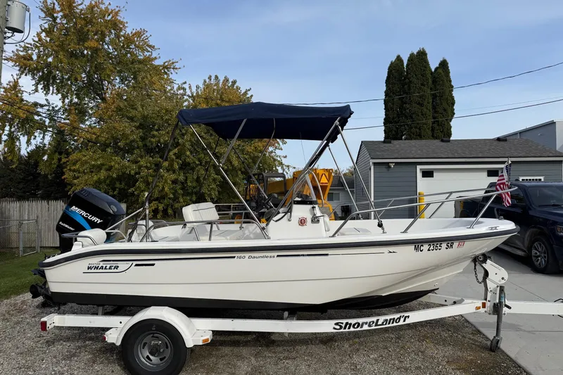 Slide: The Image of 2004 Boston Whaler 160 Dauntless boat on trailer with blue canopy and Mercury engine. - 2