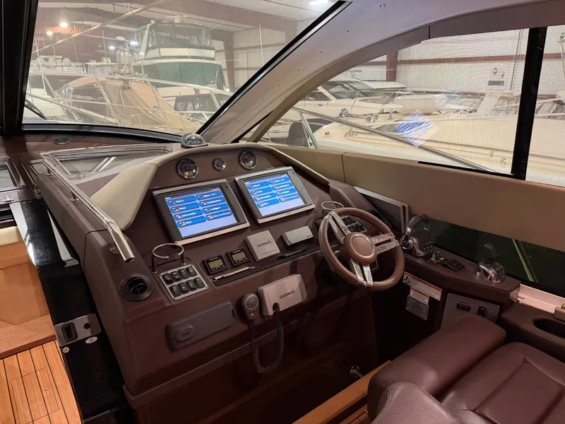 Slide: The Image of 2014 Regal 52 Sport Coupe helm with dual screens and modern controls in a marina setting. - 16