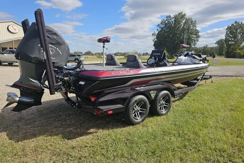 Slide: The Image of 2019 Skeeter FX21 bass boat on trailer, parked on grass under a partly cloudy sky. - 8