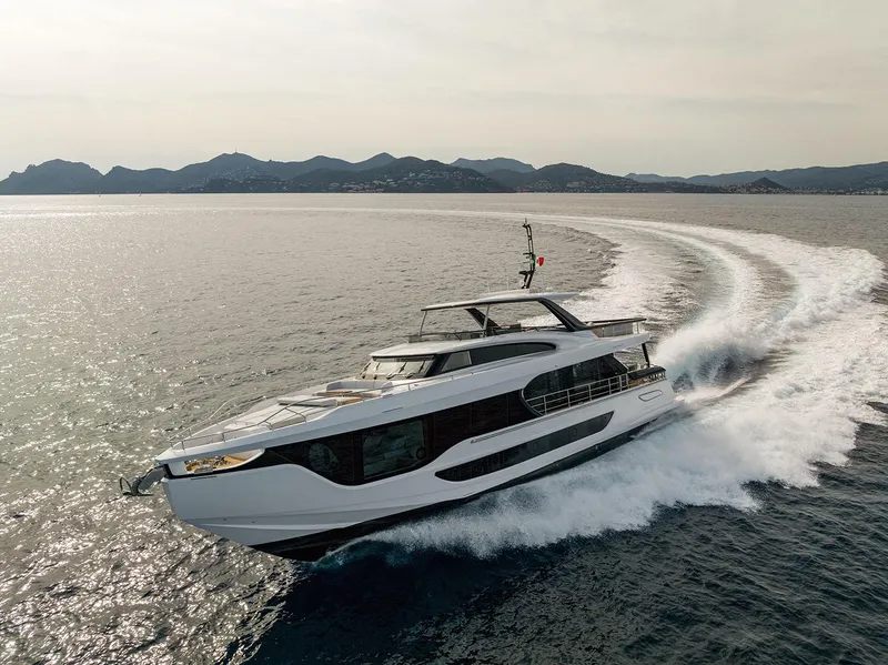 Slide: The Image of 2025 Azimut Grande 26M yacht cruising on open water, scenic mountain backdrop. - 1