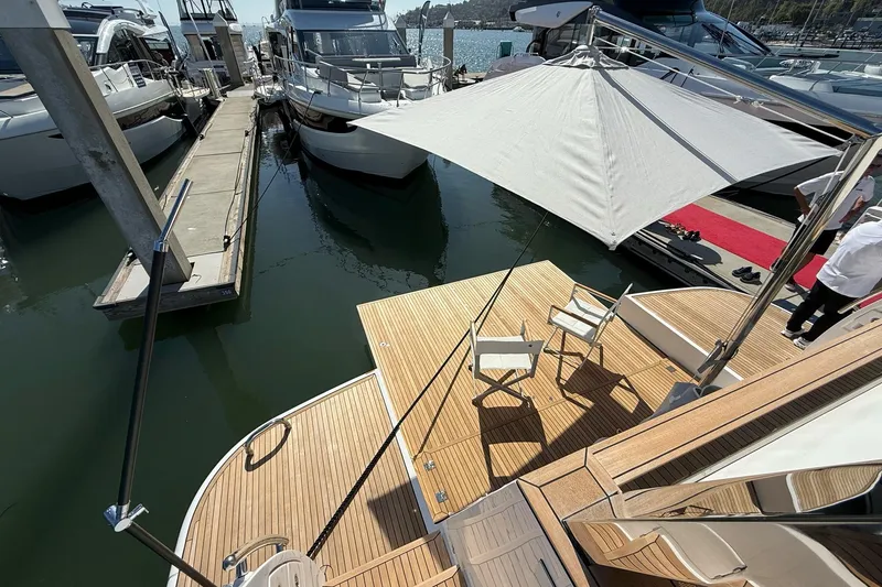 Slide: The Image of Luxury Azimut Magellano 25M yacht deck with chairs and umbrella, docked at marina, 2026 model. - 100
