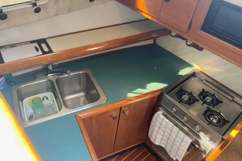 Slide: The Image of 1989 Bayliner 3288 Motoryacht interior with kitchen, stove, and cozy seating area. - 28