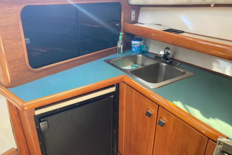 Slide: The Image of 1989 Bayliner 3288 Motoryacht kitchen with stove, sink, and wooden cabinetry. - 29