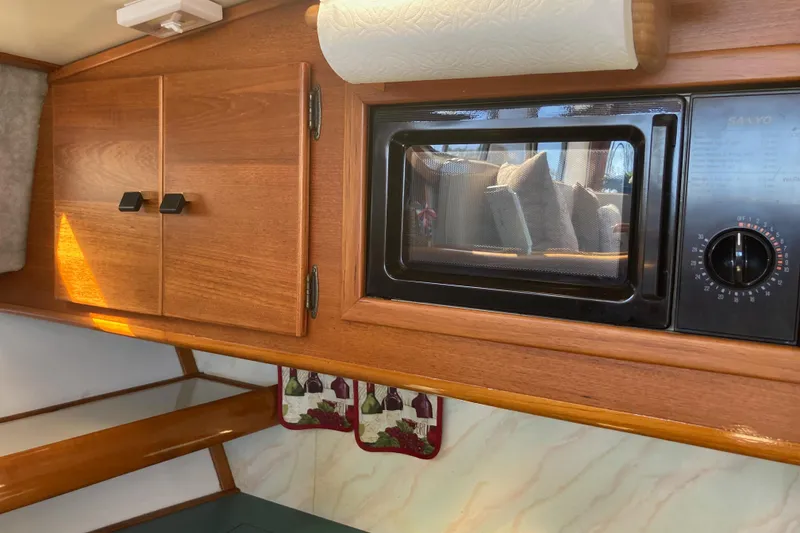 Slide: The Image of 1989 Bayliner 3288 Motoryacht kitchen with stove, wooden cabinets, and striped flooring. - 31