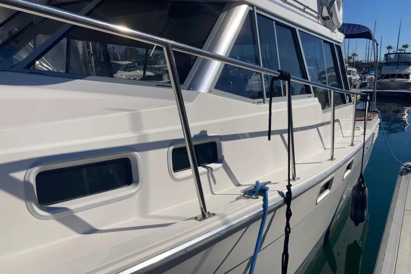 Slide: The Image of 1989 Bayliner 3288 Motoryacht docked in a marina with sailboats and clear blue sky. - 4
