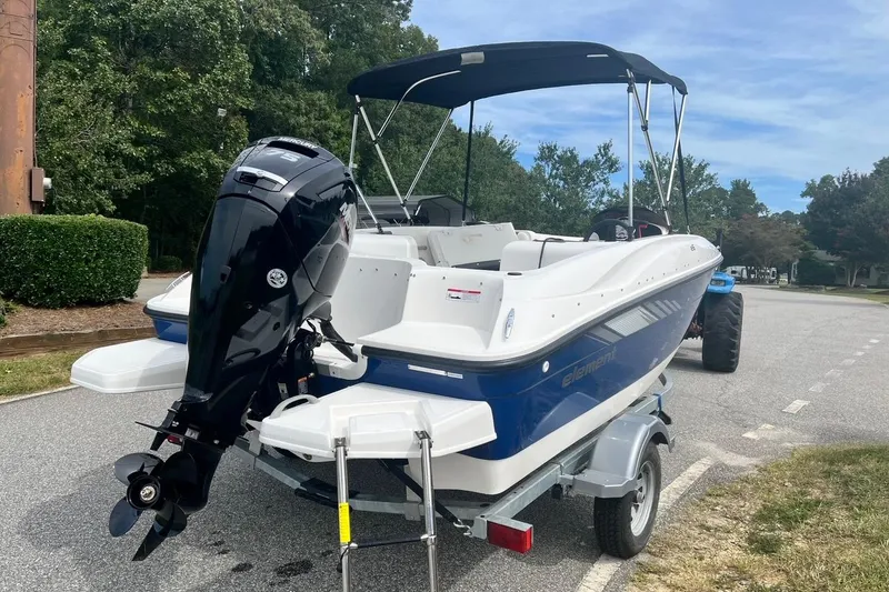 Slide: The Image of 2026 Bayliner Element E16 boat on trailer, parked on a road with trees in background. - 4