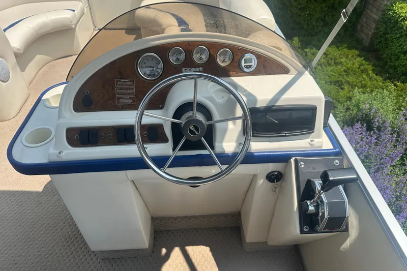 Slide: The Image of 2004 Crest 20 II LM boat dashboard with steering wheel and control panel. - 13