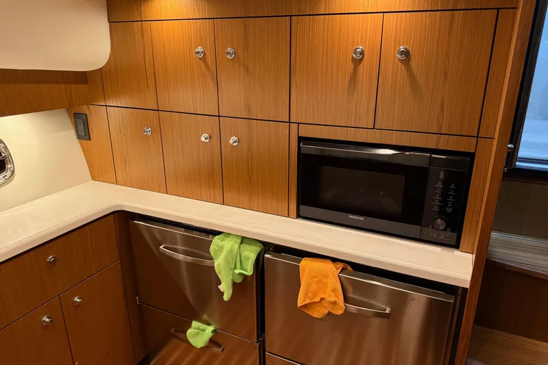 Slide: The Image of 2023 Tiara Yachts 43 Open kitchen with wood cabinets, microwave, and stainless steel appliances. - 14