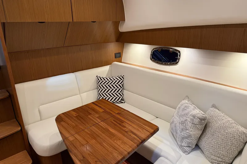 Slide: The Image of 2023 Tiara Yachts 43 Open interior with white seating, wooden table, and decorative pillows. - 16