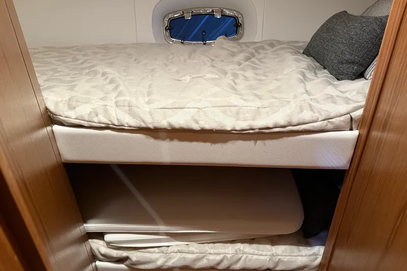 Slide: The Image of 2023 Tiara Yachts 43 Open cabin interior with cozy bedding and porthole. - 20