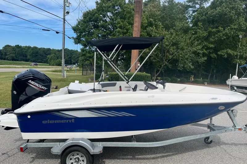 The Image of 2026 Bayliner Element E16 boat with Mercury engine on trailer, parked outdoors. - 1