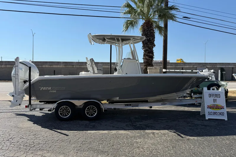 The Image of 2026 Pathfinder 2400 Open boat on trailer, displayed outdoors near palm tree. - 0