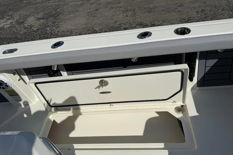Slide: The Image of 2026 Pathfinder 2400 Open boat storage compartment with key lock and rod holders. - 11