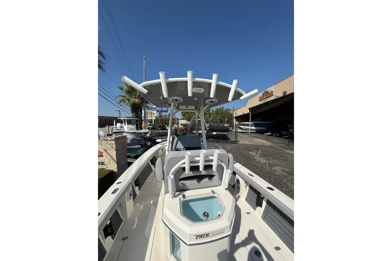 Slide: The Image of 2026 Pathfinder 2400 Open boat with T-top and rod holders, parked outdoors. - 14
