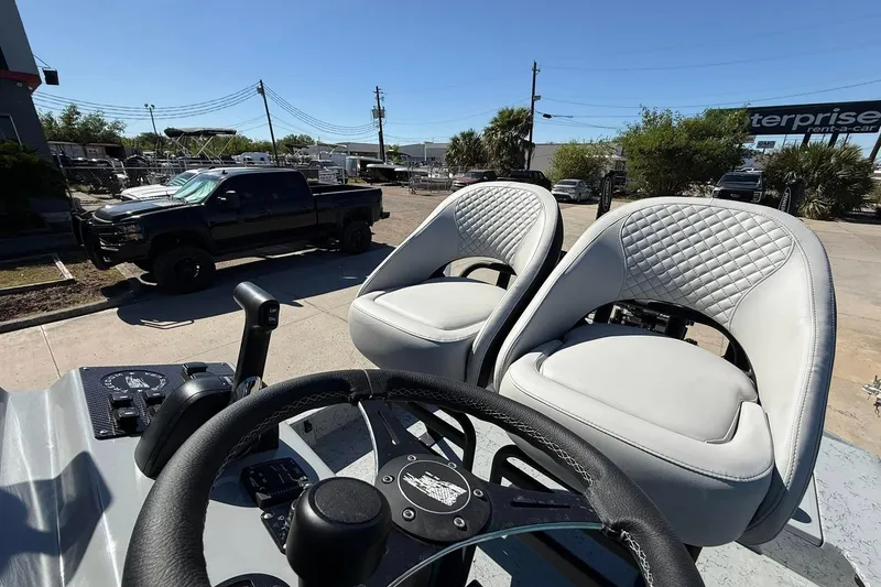 Slide: The Image of 2026 Freedom Boats 24 Defender interior with dual seats and steering wheel, parked outdoors. - 12