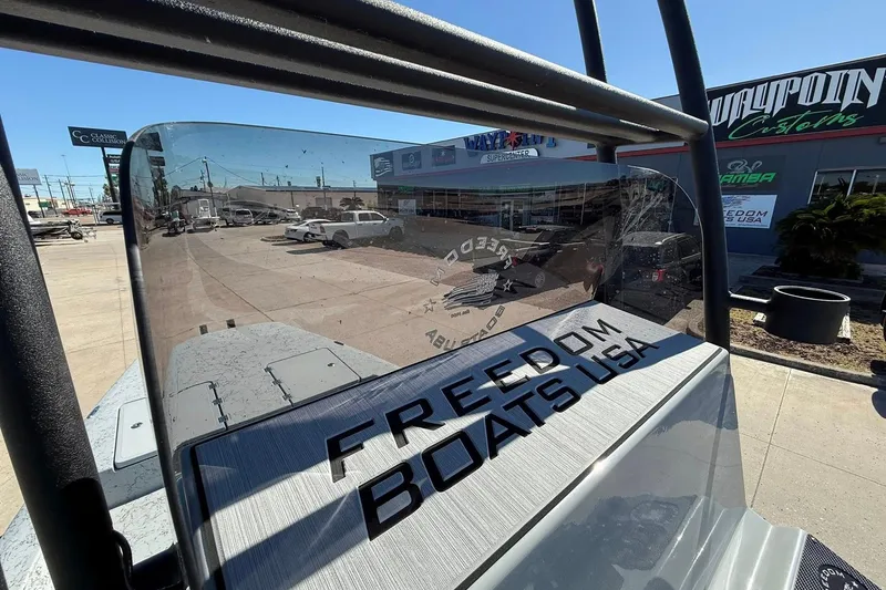 Slide: The Image of 2026 Freedom Boats 24 Defender, showcasing branding and sleek design at a dealership. - 11