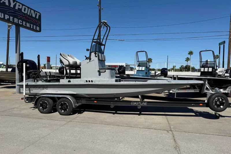 Slide: The Image of 2026 Freedom Boats 24 Defender on trailer at dealership, sunny day. - 2